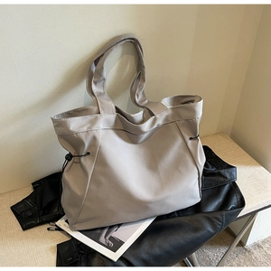Macro detail of a light grey nylon tote bag with black drawstring and smooth texture
