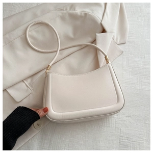 Detail of cream leather shoulder bag with gold hardware on a white blazer