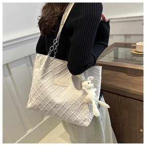 Détail du sac cabas en toile blanche texturée avec chaîne argentée et breloque lapin