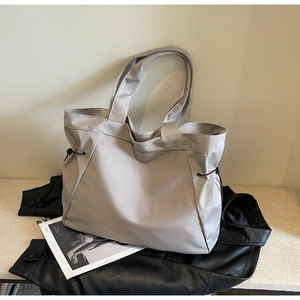 Macro view of light grey nylon tote bag showing side drawstring detail and premium texture