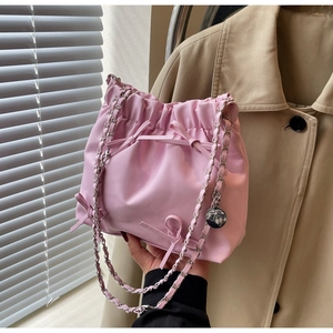 Détail du sac seau plissé rose avec nœud décoratif et bandoulière en chaîne