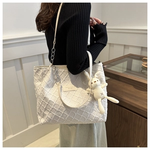 Détail du sac cabas blanc texturé avec chaîne argentée et breloque lapin en peluche