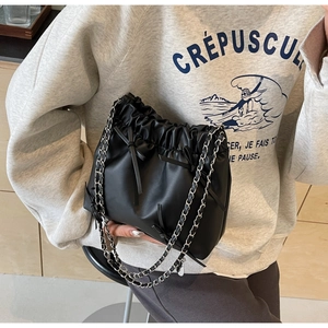 Détail du sac seau noir à cordon avec nœud en cuir et bandoulière en chaîne argentée