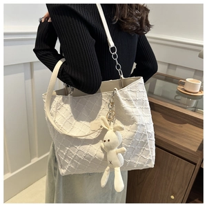 Détail du cabas en tweed blanc avec chaîne en métal et breloque lapin mignonne