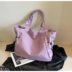Detail of light purple tote bag with side drawstrings and high-gloss nylon texture