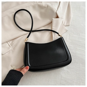 Detail of minimalist black semi-circle shoulder bag with sleek matte texture and gold hardware