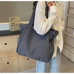 Detail of grey nylon tote bag with side drawstring accents and wide shoulder straps