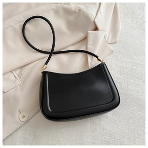 Detail view of the sleek black leather shoulder bag with golden metal ring hardware