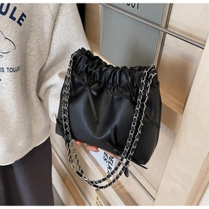 Détail du sac seau noir à cordon avec nœuds en cuir et bandoulière chaîne argent