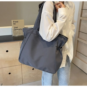 Detail of dark gray large tote bag featuring side drawstrings on durable nylon fabric