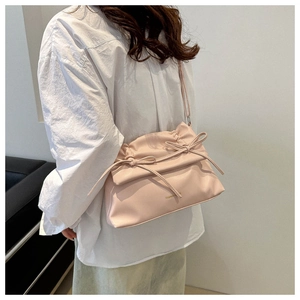 Close-up of pink faux leather bag featuring pleated flap and delicate bow accents
