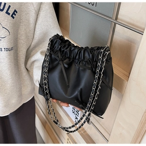 Détail du sac seau plissé noir avec nœud et bandoulière en chaîne argentée pour femme