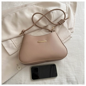 Détail du sac à bandoulière avec boucle dorée et téléphone pour comparer la taille