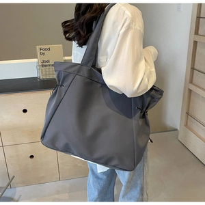 Detail of dark grey nylon tote bag with black drawstring side on a shoulder