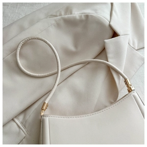 Detail view of cream white shoulder bag with gold hardware and fine leather stitching