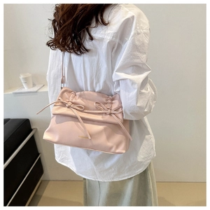 Detail of soft pink pleated shoulder bag featuring a decorative bow and embossed text