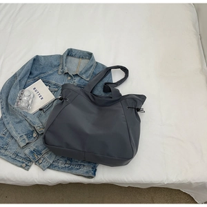 Detail of dark gray nylon tote bag with side drawstring and water-resistant texture