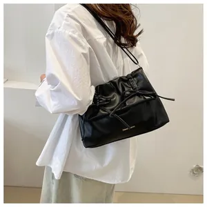 Detailed view of the pleated black PU leather bag with bow drawstring on model