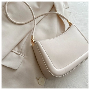 Detailed view of cream leather shoulder bag with sleek hardware and refined texture