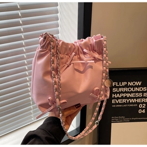 Détail du sac seau plissé rose avec nœuds délicats et bandoulière en chaîne argentée