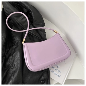 Detail of lavender underarm bag with golden hardware on a stylish black leather coat