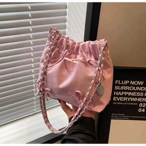 Vue détaillée d'un sac seau rose plissé avec nœud décoratif et bandoulière en chaîne
