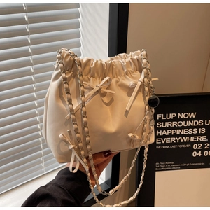 Détail d'un sac seau plissé avec nœuds décoratifs et bandoulière en chaîne argentée