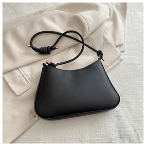 Détail d'un sac sous le bras noir minimaliste avec bandoulière fine et finitions dorées