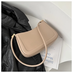 Close-up of beige leather handbag with rectangular embossing and gold metal buckles