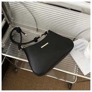 Détail d'un sac à bandoulière en cuir noir avec boucle dorée et sangle nouée