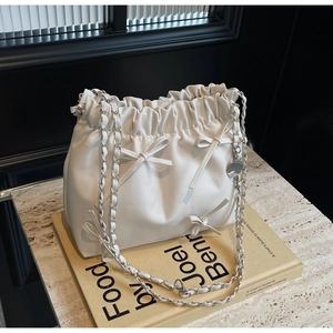 Détail d'un sac à main plissé en cuir blanc avec nœuds et bandoulière en chaîne