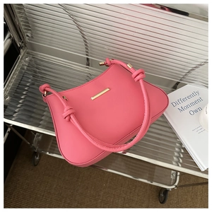 Détail macro d'un sac à main en cuir PU rose pêche avec barre dorée et poignées nouées