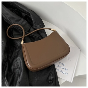 Close-up of brown leather shoulder bag with gold hardware on a black jacket
