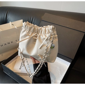 Détail du sac seau plissé blanc avec nœuds en cuir et bandoulière chaîne argent