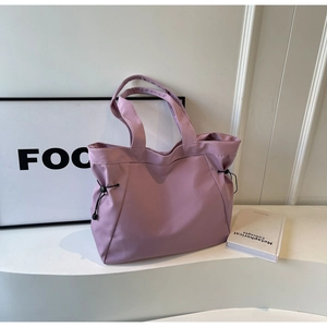 Detail of purple nylon tote bag featuring side drawstring closure and large capacity