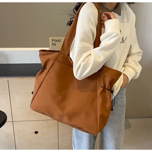 Detail of tan large capacity tote bag with functional side drawstrings and wide shoulder strap