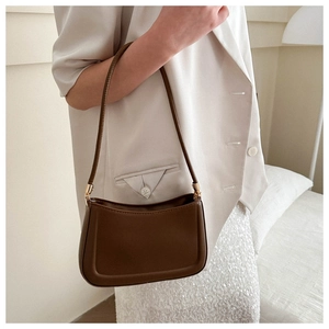Detail of dark brown leather shoulder bag featuring fine stitching and gold metal hardware