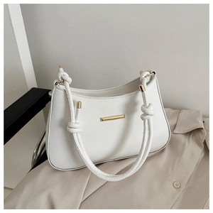 Detailed view of white leather handbag with gold metal bar and knotted tubular handle