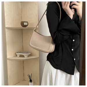 Minimalist beige leather baguette bag with gold accents shown in a stylish mirror selfie