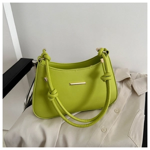 Detail of lime green faux leather shoulder bag with knot handle and gold hardware accent