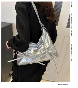 Detail of silver metallic hobo bag with pleated sides and bow accents in Y2K style