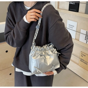 Détail du sac seau plissé argenté avec nœud et bandoulière en chaîne