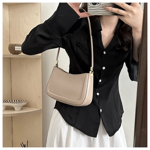 Close-up of beige moon bag with smooth leather finish and golden square hardware