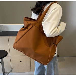 Detailed side view of brown nylon tote bag with drawstring on stylish woman in cafe
