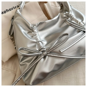 Detail of silver pleated tote bag featuring a metallic finish and bow ribbon decoration