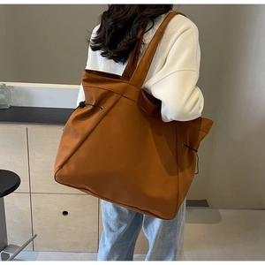 Caramel brown large tote bag shown on shoulder in a minimalist indoor setting
