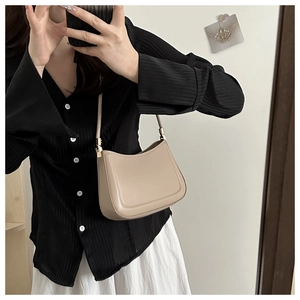 Mirror selfie showing the beige leather shoulder bag with a stylish striped outfit
