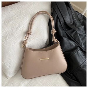 Vue détaillée du sac beige avec boucle en métal doré et bandoulière nouée sur tissu doux