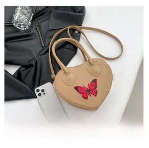 Detail of heart-shaped handbag featuring a red butterfly print and top handle