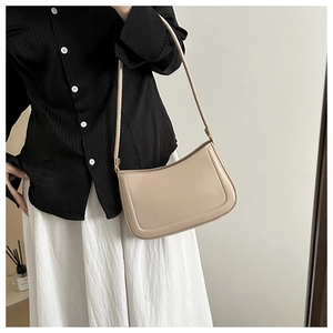 Detail of minimalist beige baguette bag styled with striped shirt and white skirt